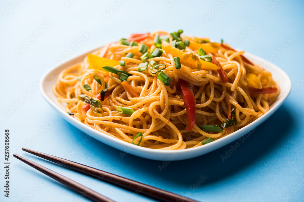 Schezwan Noodles or vegetable Hakka Noodles or chow mein is a popular Indo-Chinese recipes, served in a bowl or plate with wooden chopsticks. selective focus Schezwan Noodles or vegetable Hakka Noodles or chow mein is a popular Indo-Chinese recipes, served in a bowl or plate with wooden chopsticks. selective focus