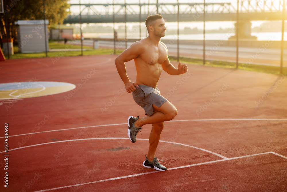 Fitness training outdoors. Handsome man working exercises in early morning with sunrise. Muscular man training outside. Sunny fitness morning.