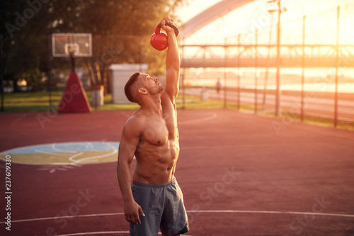 Handsome man working exercises in early morning with sunrise. Fitness training outdoors.