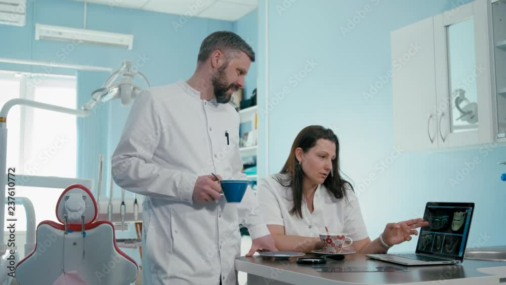 Two Dentsts Doctors are Working Discussing Dental CT scan using Laptop in the Medic Healthcare Clinic