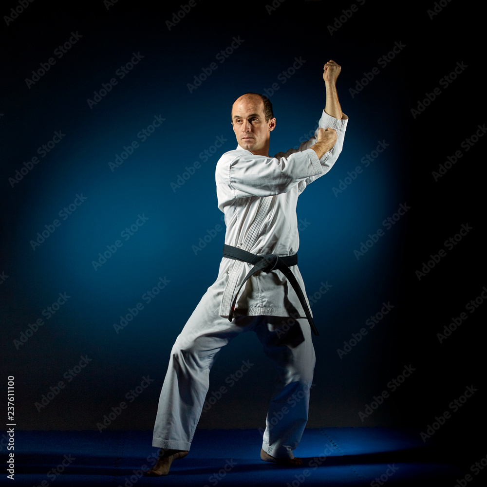 An active athlete trains formal karate exercises on a blue tatami