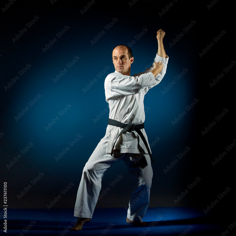 An active athlete trains formal karate exercises on a blue tatami An active athlete trains formal karate exercises on a blue tatami