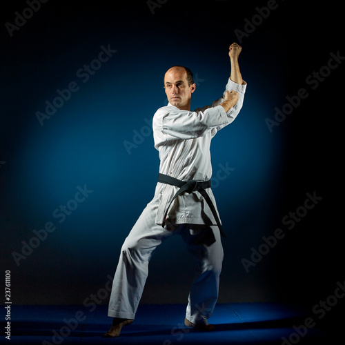 An active athlete trains formal karate exercises on a blue tatami