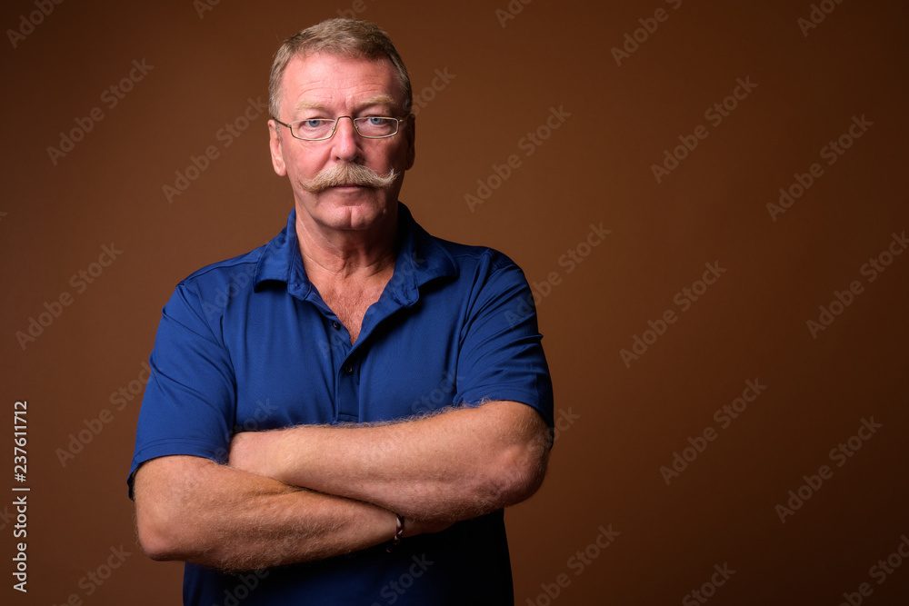Handsome senior man with mustache wearing eyeglasses with arms crossed Handsome senior man with mustache wearing eyeglasses with arms crossed