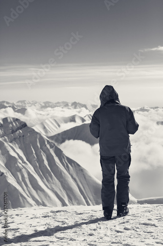 Skier on top of snowy mountains in clouds