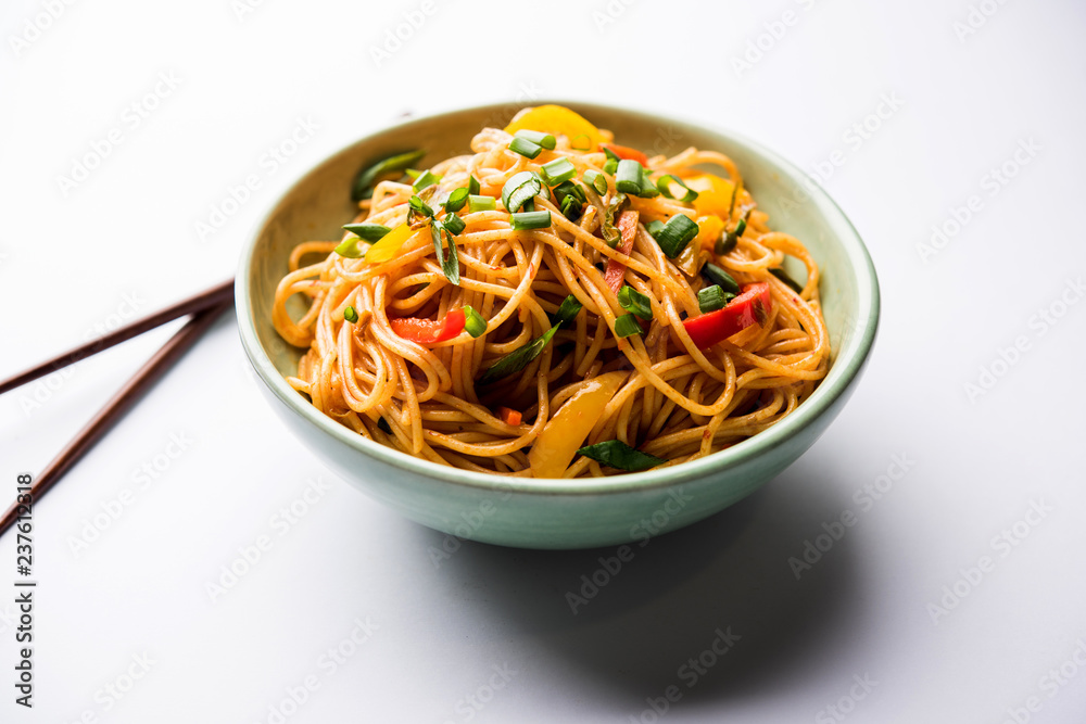 Schezwan Noodles or vegetable Hakka Noodles or chow mein is a popular Indo-Chinese recipes, served in a bowl or plate with wooden chopsticks. selective focus Schezwan Noodles or vegetable Hakka Noodles or chow mein is a popular Indo-Chinese recipes, served in a bowl or plate with wooden chopsticks. selective focus
