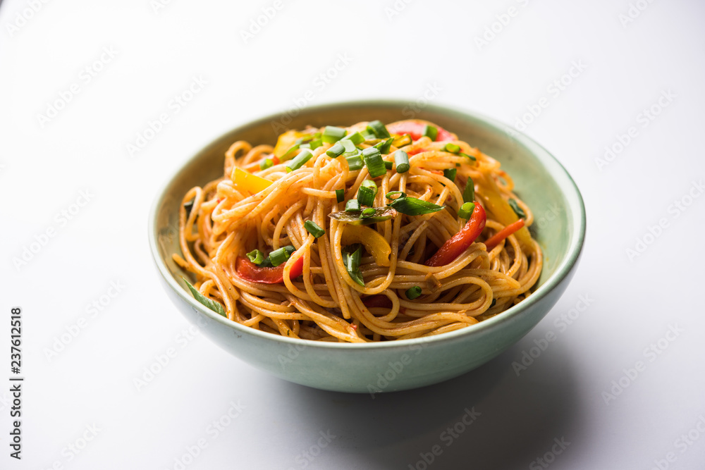 Schezwan Noodles or vegetable Hakka Noodles or chow mein is a popular Indo-Chinese recipes, served in a bowl or plate with wooden chopsticks. selective focus