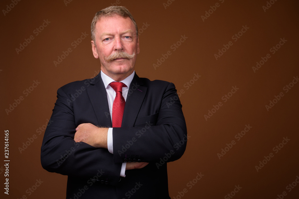 Handsome senior businessman wearing suit and tie with arms crossed Handsome senior businessman wearing suit and tie with arms crossed