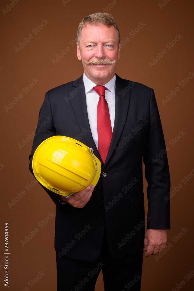 Handsome senior construction businessman with mustache holding hardhat Handsome senior construction businessman with mustache holding hardhat