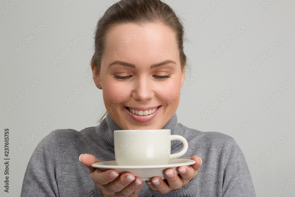 Hübsche Frau hält lächelnd eine Kaffeetasse in der Hand Hübsche Frau hält lächelnd eine Kaffeetasse in der Hand