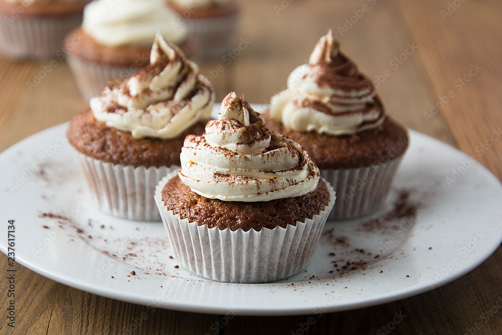 Chocolate cupcakes with whipped cream on rustic wooden table. Homemade dessert.