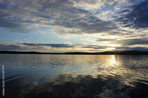 Beautiful sunset over a lake  with clouds and reflection in Finland © Christoph Nanz