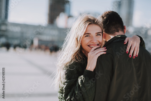 Beautiful young woman hugging her boyfriend on blurred background