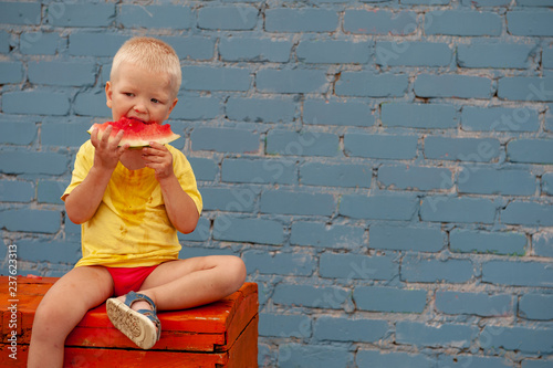 Funny village children eat watermelon sitting on old chest in courtyard of village house. Boys brothers are happy together. School holidays in village. Parents take care of kids. Eco-friendly products photo