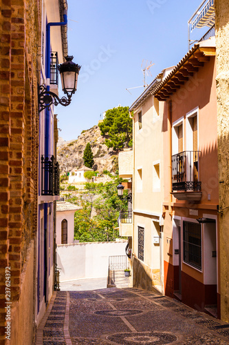 The cozy street of the old European city of Relleu is paved with cobblestones in the form of a picture. Mediterranean architecture in Spain. photo