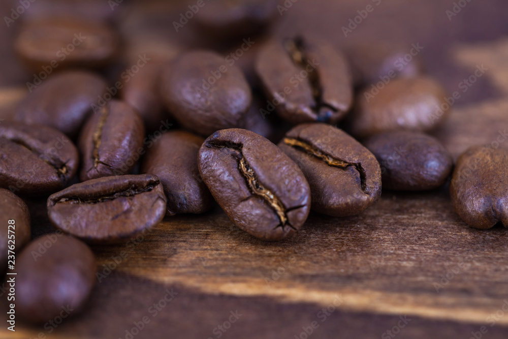 Naklejka premium Roasted coffee beens on a wooden table, close up
