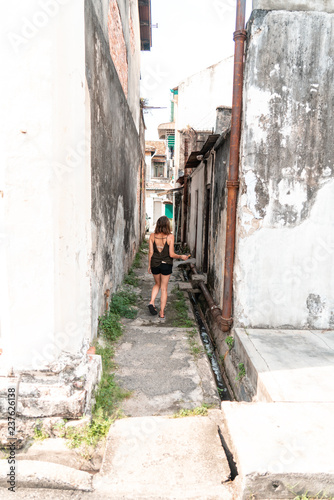 A woman walks down an ancient walkway in a historic colonial village