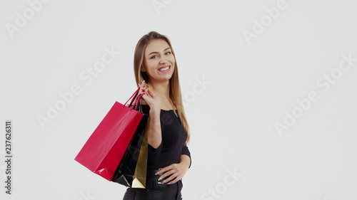 Woman in black dress, holding black, red and gold shopping bag isolated on white background in black friday holiday or christmas