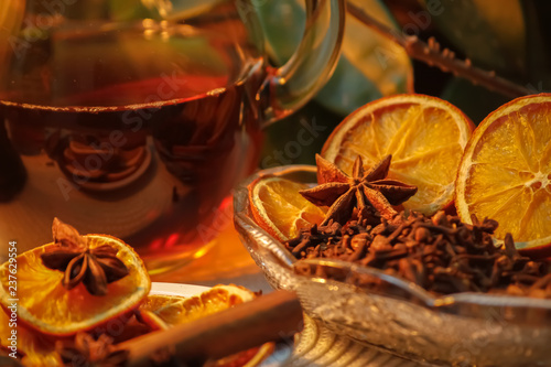 Beautiful composition with anise, cloves, cinnamon stick and powder, tea and dried orange. Wooden table, rustic background and candle light. Close-up.