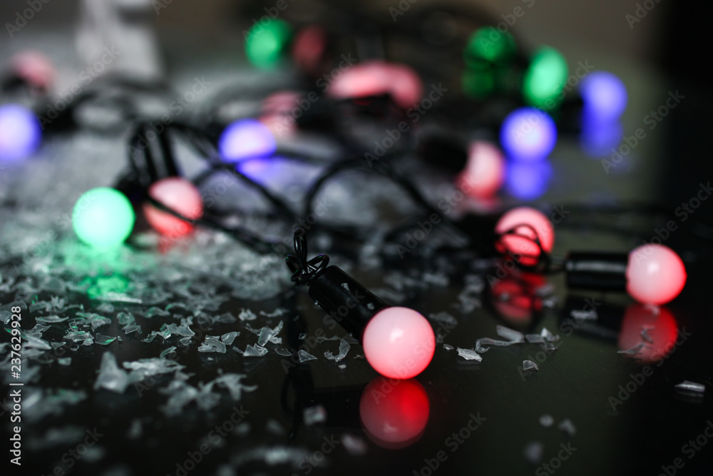 Multicolored garland in artificial snow on black background. Concept New year. Multicolored garland in artificial snow on black background. Concept New year.
