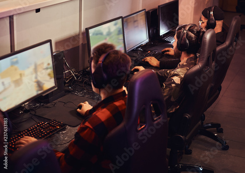 Schilderij op canvas A team of professional cyber sportmans, trains for the championship, plays in a multiplayer video game on pc in a gaming club or internet cafe