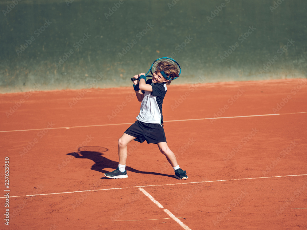 Boy playing tennis on hard court Boy playing tennis on hard court