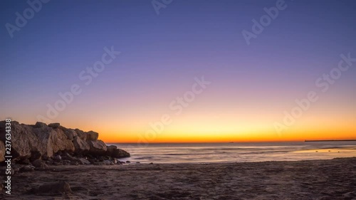 Night to day 4K time lapse of the sun rising over the Mediterranean Sea by Valencia Spain with Venus in view at the start, boats on the horizon and a rocky sea break