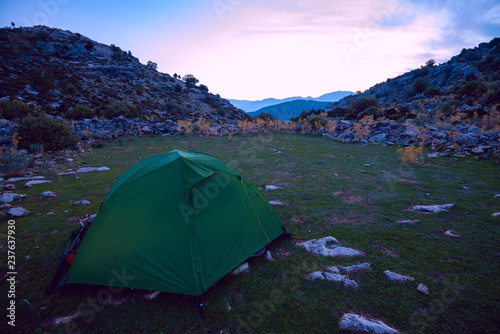 Tent on a green glade among rock hills
