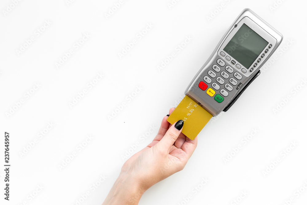 Pay by payment terminal. Woman's hand inserts credit card to terminal on white background top view copy space