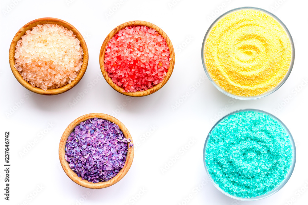 Spa salt background. Colorful spa salt in bowls on white background top view. Yellow, turquoise, pink, purple spa salt
