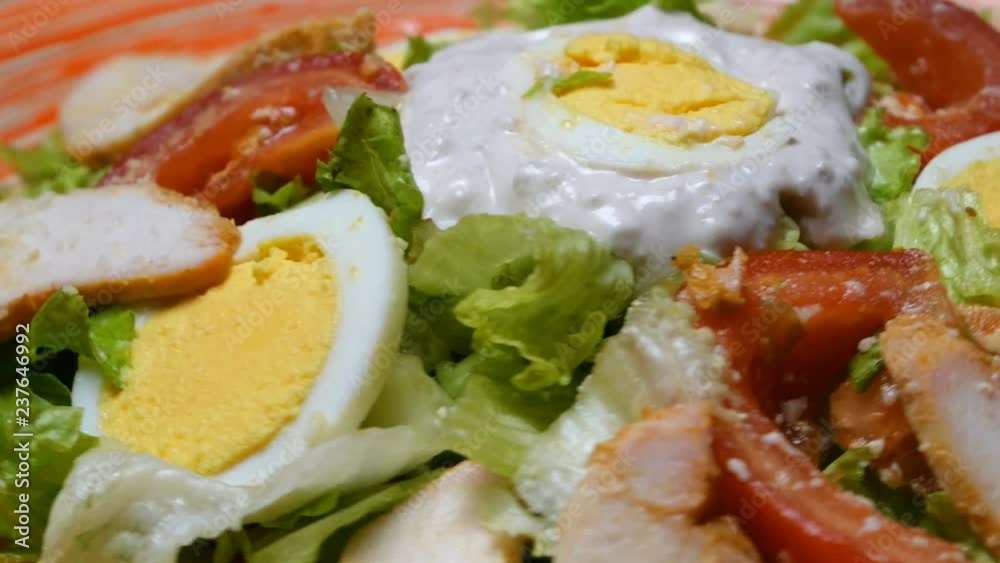 Caesar salad in red plate. Caesar salad consists of roasted chicken breast, iceberg lettuce, tomato, parmesan cheese. Popular dish of European cuisine and cuisines of other countries of world. Caesar salad in red plate. Caesar salad consists of roasted chicken breast, iceberg lettuce, tomato, parmesan cheese. Popular dish of European cuisine and cuisines of other countries of world.