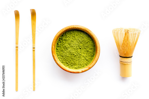 Matcha powder in bowl near specail stick and whisk on white background top view