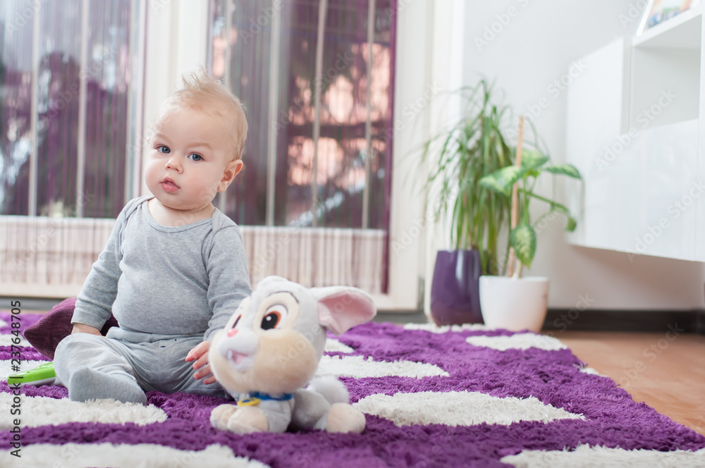 Happy baby boy sitting on the floor and playing with his toy. Happy baby boy sitting on the floor and playing with his toy.
