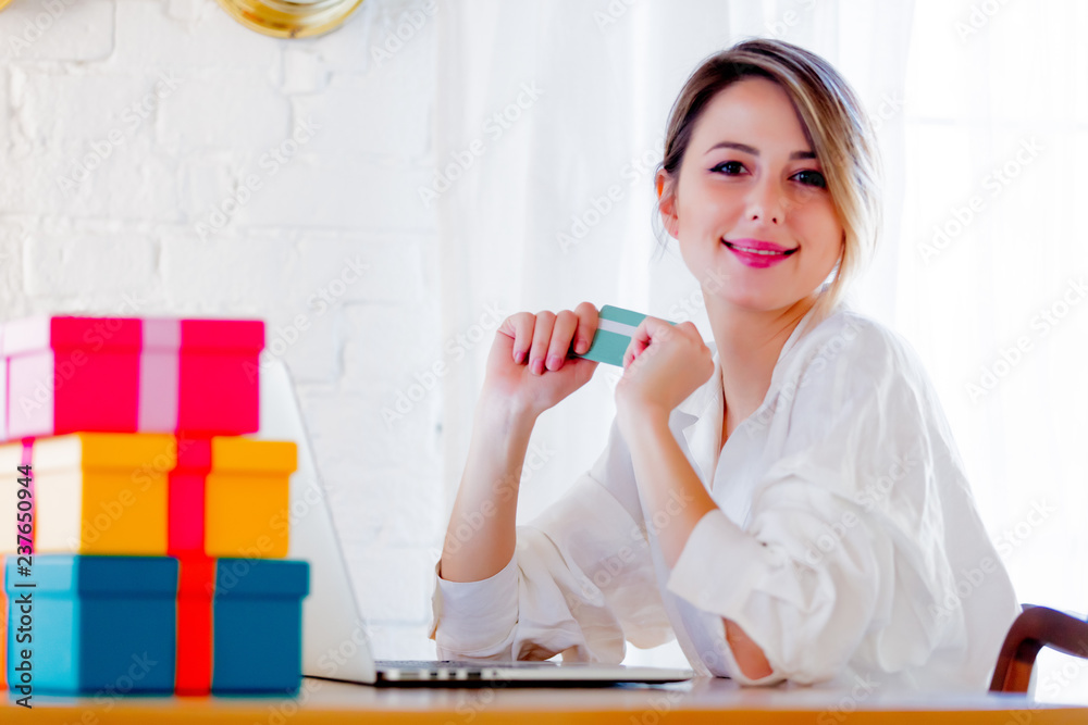 Young girl with holiday gifts and laptop computer holding a credit card. Business, education, shopping and other concept