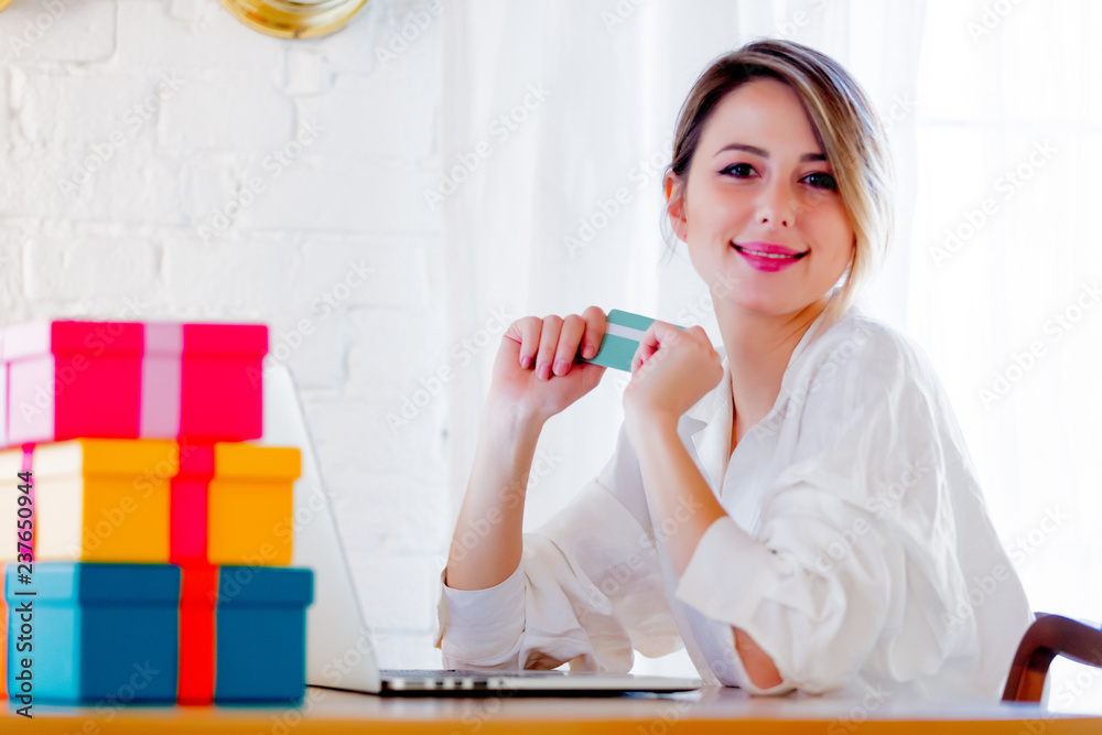 Young girl with holiday gifts and laptop computer holding a credit card. Business, education, shopping and other concept Young girl with holiday gifts and laptop computer holding a credit card. Business, education, shopping and other concept