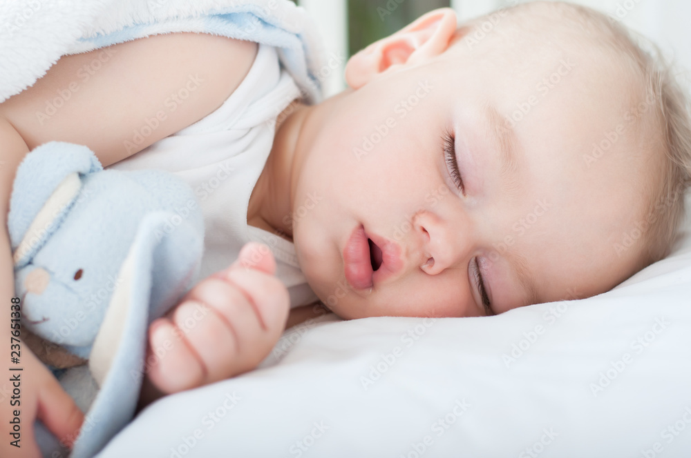 Beautiful baby boy laying down in his bed and sleeping. Close up. Beautiful baby boy laying down in his bed and sleeping. Close up.
