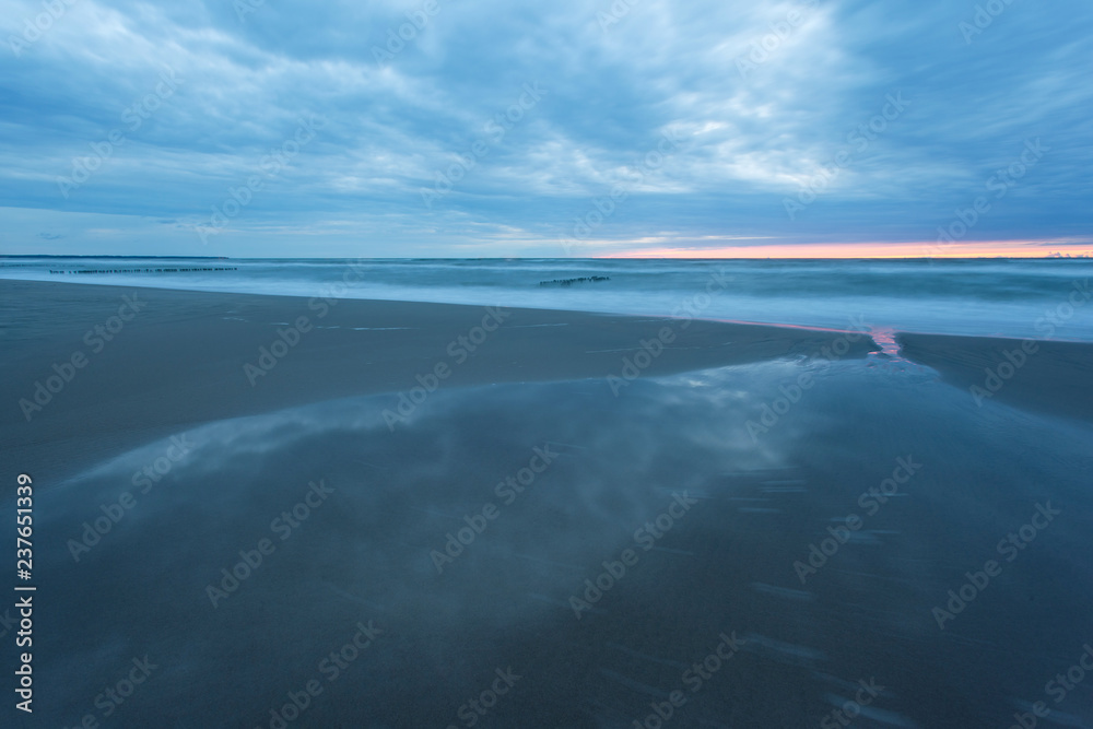 landscape at dusk, sandy beach and a smooth sea surface during the landscape at dusk, sandy beach and a smooth sea surface during the