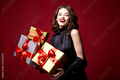 Beautiful young pretty woman with a bright evening make-up of shiny red lipstick on the lips brunette curly hair festive mood winter Christmas New Year St. Valentine's Day and birthday gift surprise.