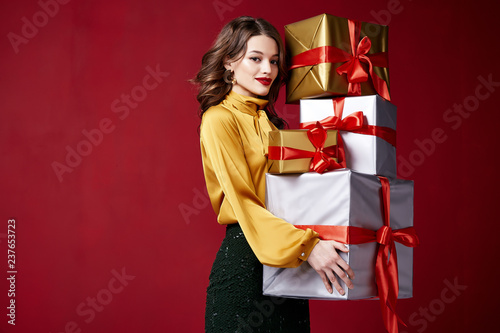 Beautiful sexy young brunette girl with wavy hair bright evening make-up red lips long fluffy eyelashes hold gift box holiday New Year  joy fun happy merry Christmas Eve party celebration.