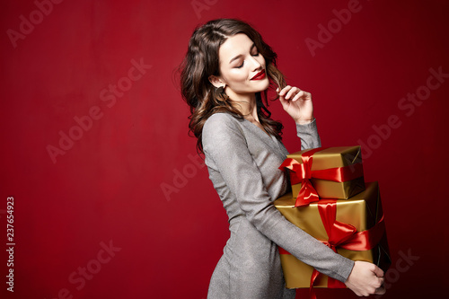 Beautiful sexy young brunette woman hair bright evening make-up red lips long fluffy eyelashes hold gift box holiday New Year  joy fun happy merry Christmas Eve party celebration St. Valentine's Day.