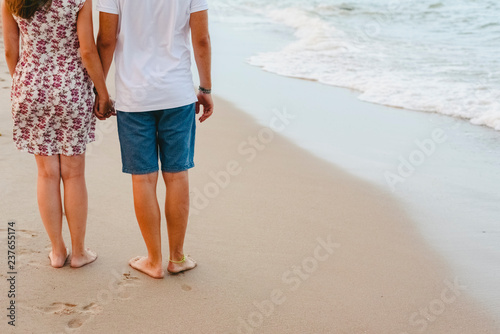 Couple in love walking in autumn on the barefoot beach.