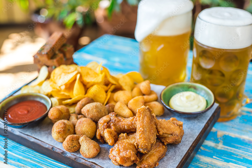 beer in glasses with snacks, chicken nuggets, chips and sauces beer in glasses with snacks, chicken nuggets, chips and sauces