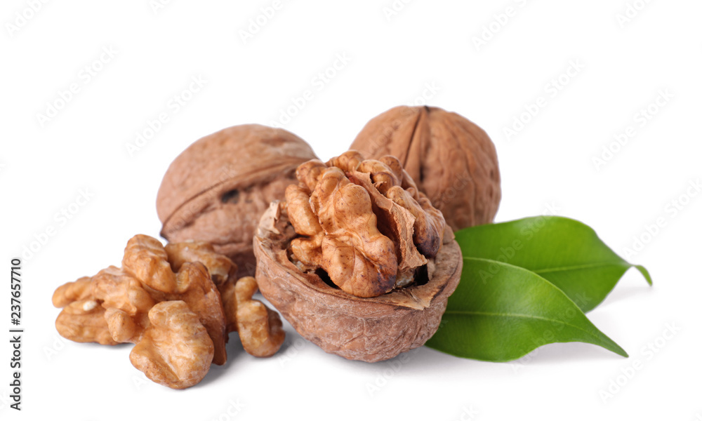 Walnuts in shell, kernels and green leaves on white background Walnuts in shell, kernels and green leaves on white background