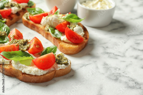 Toasted bread with tasty cream cheese and tomatoes on marble table. Space for text
