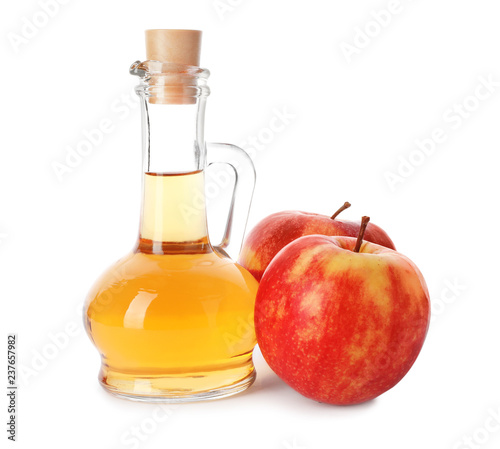Glass jug of vinegar and fresh apples on white background