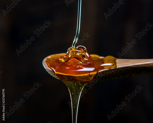 Strand of Honey Piles Into Wooden Spoon