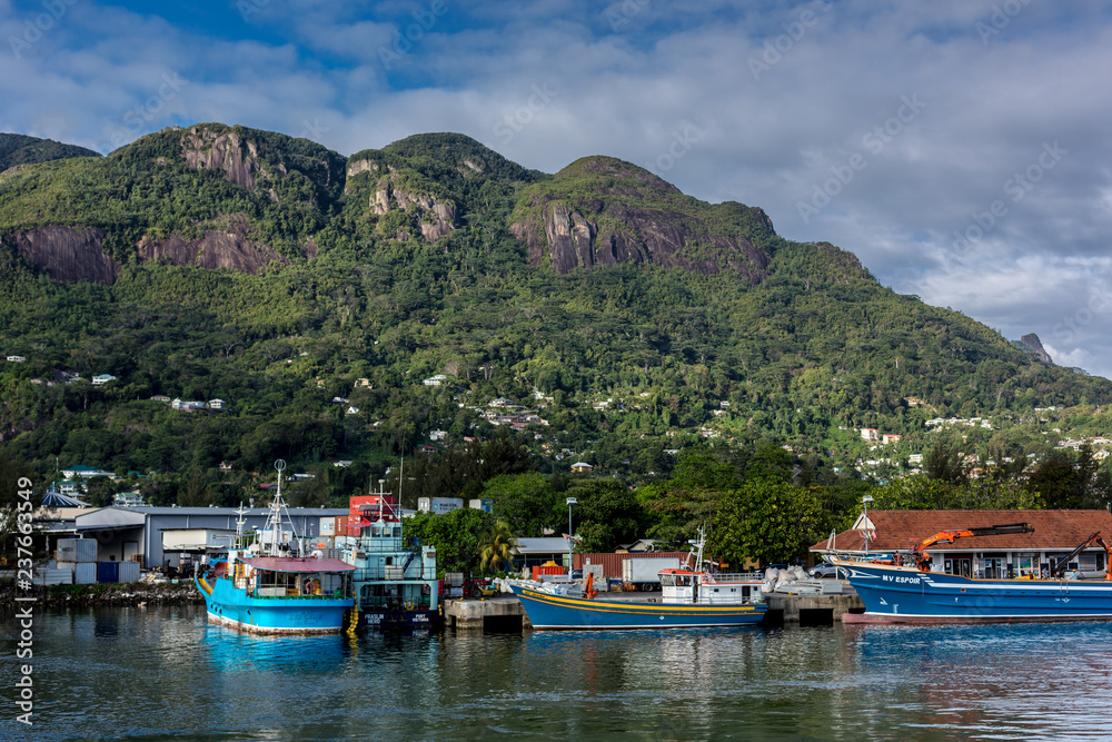 Mahe, Seychelles - Oct 26th 2018 - Fisherman boats in the Mahe's port in Seychelles with mountains covered with green vegetation in the background