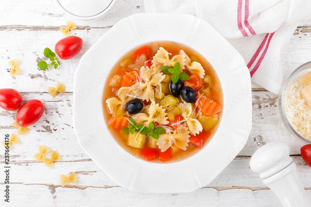 Minestrone, vegetarian soup with pasta and vegetables on white wooden rustic background. Traditional italian food. Top view Minestrone, vegetarian soup with pasta and vegetables on white wooden rustic background. Traditional italian food. Top view