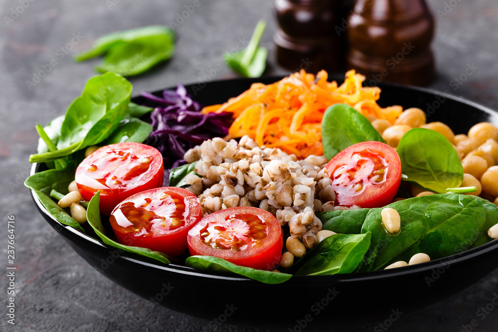 Healthy vegetarian dish with buckwheat and vegetable salad of chickpea, kale, carrot, fresh tomatoes, spinach leaves and pine nuts. Buddha bowl. Balanced food. Delicious detox diet