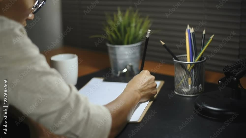 Asian woman writing down on a white blank notebook on table Asian woman writing down on a white blank notebook on table